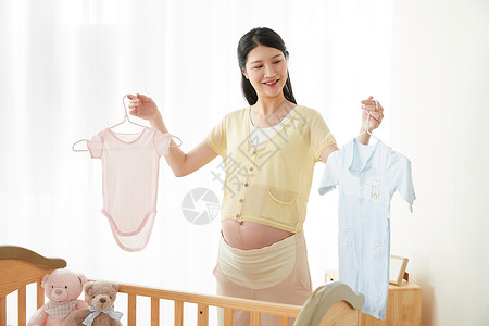母爱摇篮孕妇拿着宝宝衣服背景