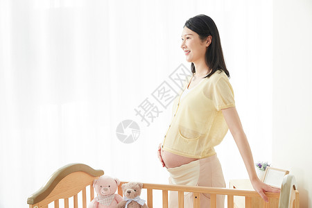 母爱摇篮孕妇站在婴儿床旁背景