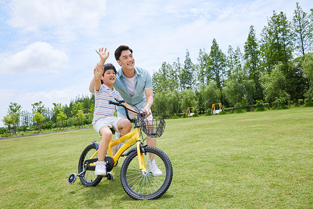 打招呼的小男孩爸爸陪伴小男孩骑自行车背景