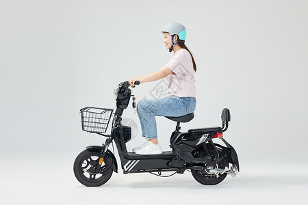 青年女性戴头盔骑电动车背景图片