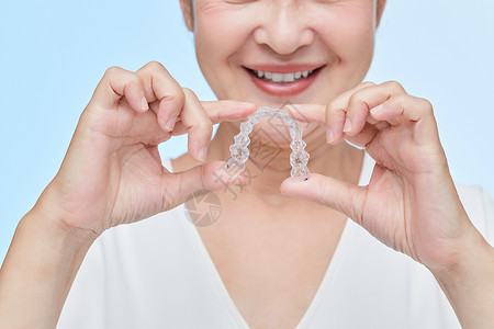牙齿形状中年女性拿牙套展示背景