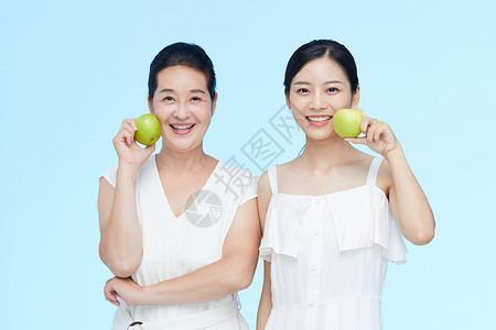 美女拿苹果年轻美女和中年女士一起拿苹果展示背景