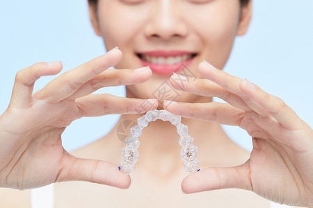 牙齿形状女性手拿牙套展示特写背景