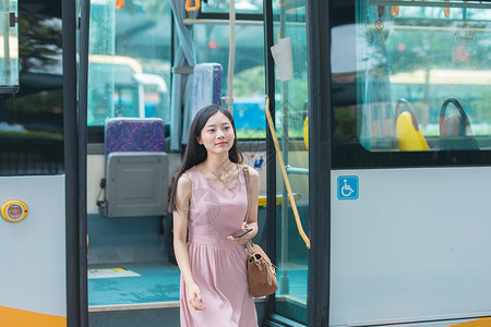 公交车到站下车的年轻女性背景图片