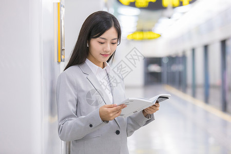 商务女性在地铁站内看书等待图片