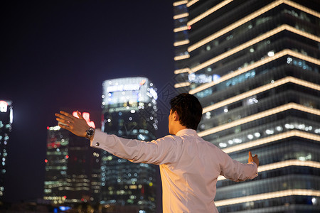 夜晚天桥上的都市商务男性张开双臂背影图片