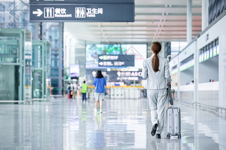 机场商务女性白领拖行李箱出行背景图片