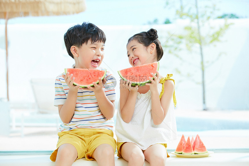 小男孩和小女孩坐在泳池边开心吃西瓜图片