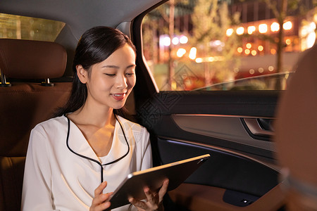 商务女性晚上在车上使用平板汽车高清图片素材