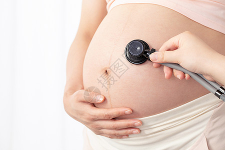 孕妇拿听诊器听肚子的胎动高清图片