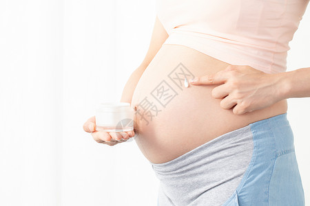 修复妊娠纹孕妇给肚子上涂抹润肤乳背景
