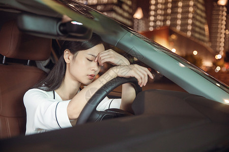 累趴下女性夜晚开车疲劳驾驶背景