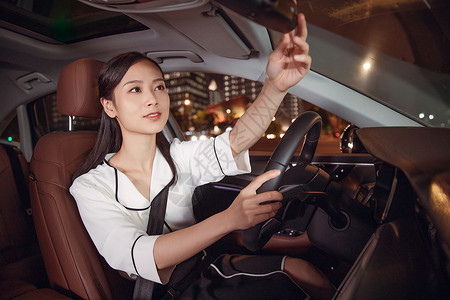 白领女性司机夜间驾车检查后视镜汽车驾驶高清图片素材