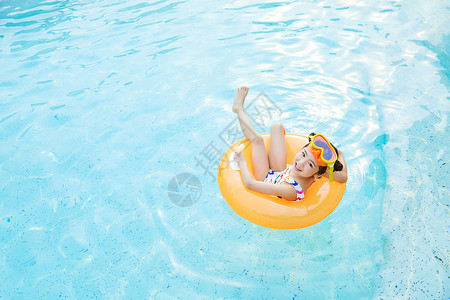 黄色小鱼游泳圈小女孩躺在泳池里的游泳圈上背景