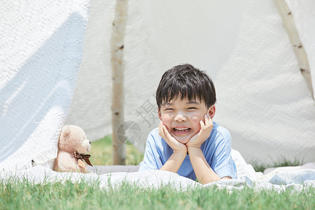 小男孩趴在草坪上开心大笑图片