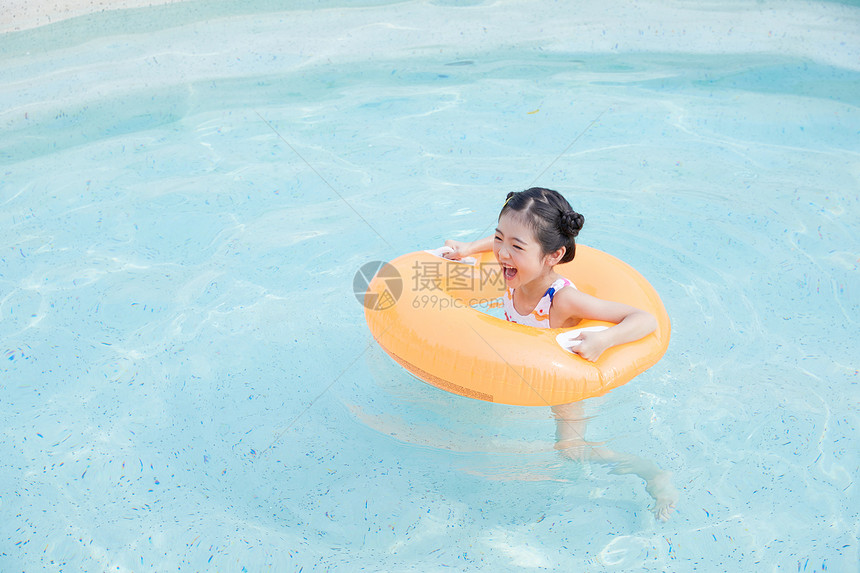 小女孩在泳池里面用游泳圈游泳图片