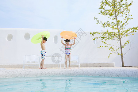 小男孩和小女孩拿着泳圈在泳池边行走友谊高清图片素材