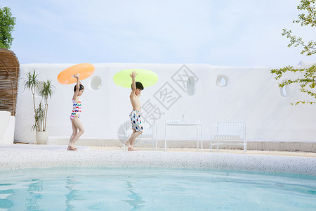小男孩拿着泳圈小男孩和小女孩拿着泳圈在泳池边行走背景
