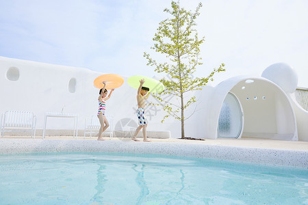 小男孩和小女孩拿着泳圈在泳池边行走度假高清图片素材