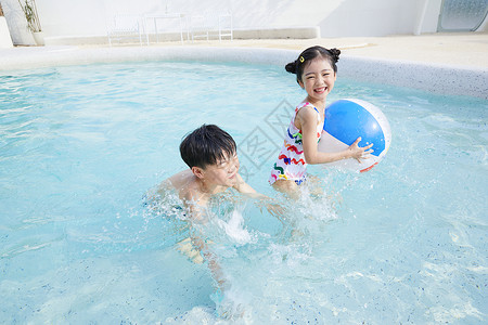沙滩玩球的孩子小男孩和小女孩在泳池玩球背景