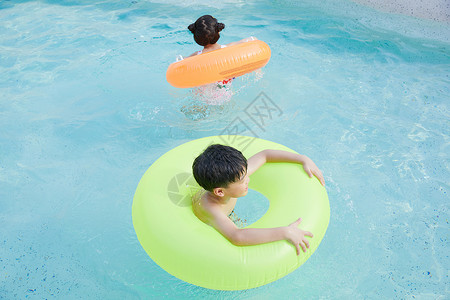 快乐儿童使用游泳圈在泳池玩耍图片素材