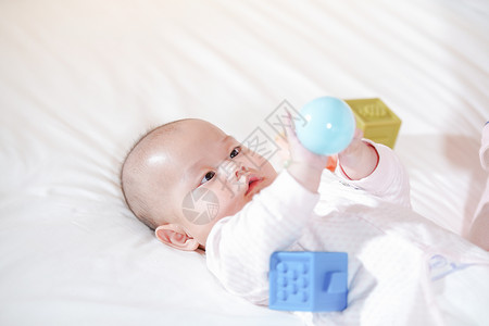 宝宝趴在床上开心的玩球玩玩具背景图片