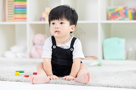 小孩子背景可爱幼儿宝宝坐地毯上吃糖果背景