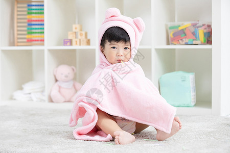 幼儿宝宝裹着浴巾在地毯上嬉戏背景图片