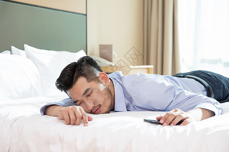 商务男性酒店出差趴床上休息商旅高清图片素材