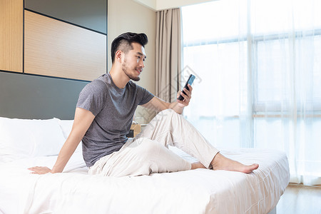 商务男性躺在酒店床上看手机客房高清图片素材