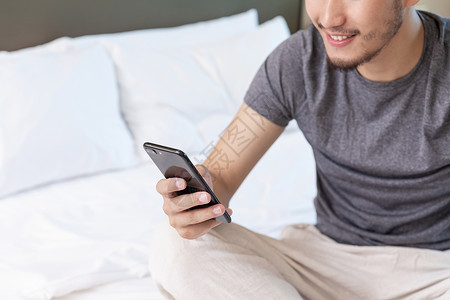 青年男性坐在酒店床上看手机背景图片