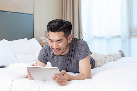 商务男性躺在酒店床上看手机客房高清图片素材