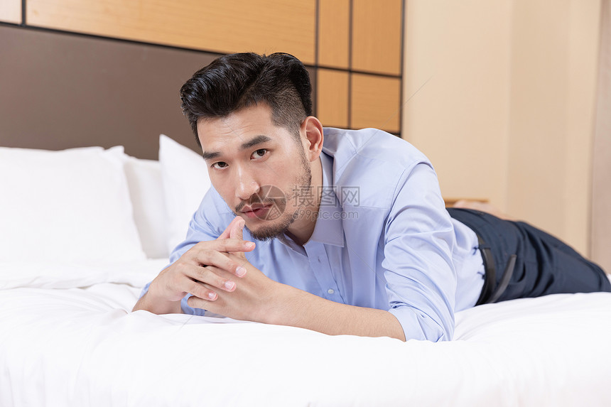 商务男性酒店出差趴在床上图片