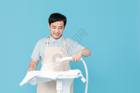 使用挂烫机熨烫衣服的家政服务男性背景