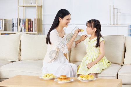 吃月饼的小女孩年轻妈妈喂女儿吃月饼背景