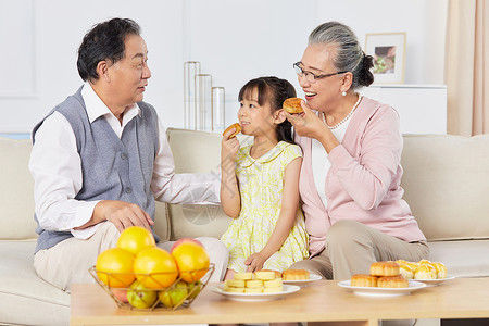 吃月饼的小女孩小女孩和爷爷奶奶中秋节一起吃月饼背景