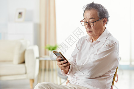 老年男性坐椅子上玩手机图片
