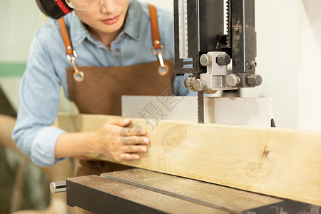 女性工匠用切割机锯木头特写图片