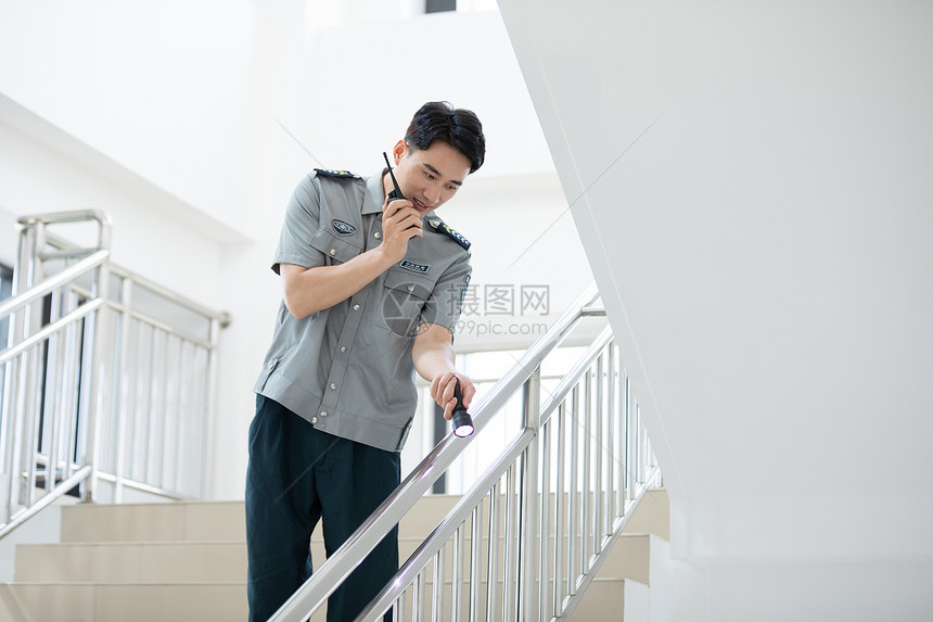 保安手拿对讲机在楼道巡视图片