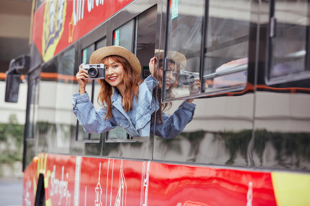 秋季上新品拿相机在旅游大巴上拍照的美女背景