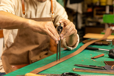 男性皮匠给皮带打孔定做高清图片素材