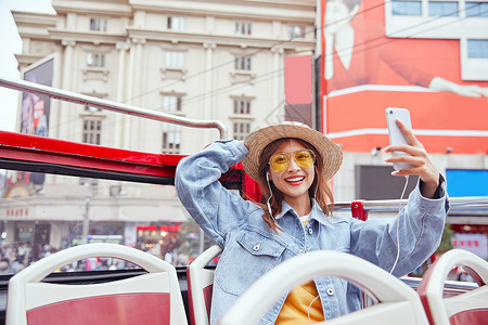 秋季旅行季在观光大巴上用手机自拍的女青年背景