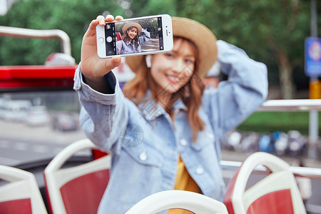 秋季旅行季在观光大巴上用手机自拍的女青年背景