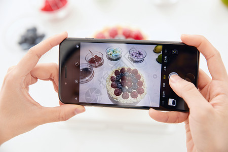 女性拿手机给手工蛋糕拍照特写图片