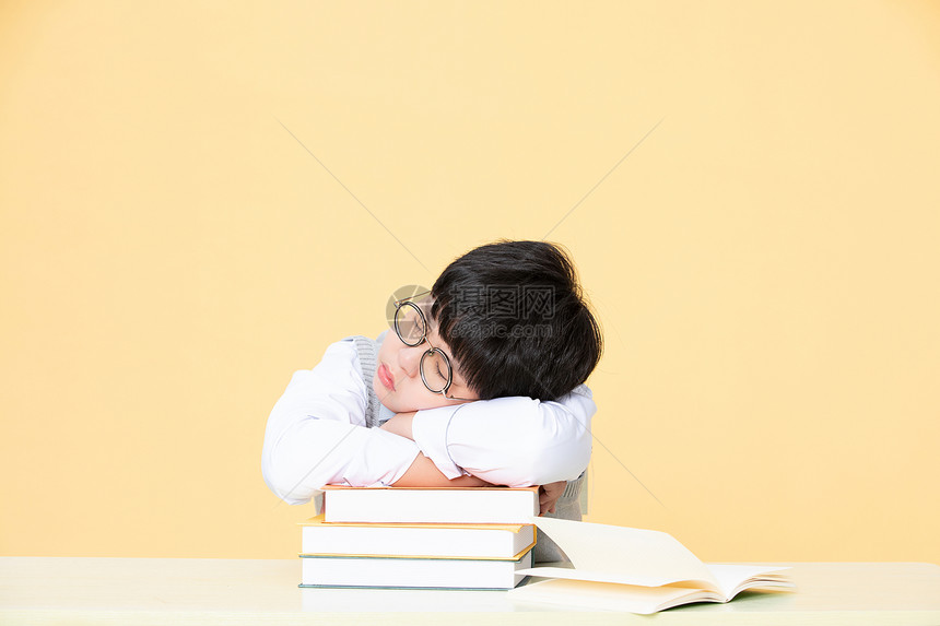 为学习发愁的小男孩把头趴在书上图片