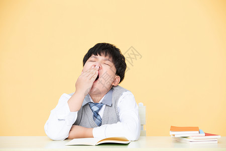 儿童学习用品小男孩学习中打哈欠精神不集中背景