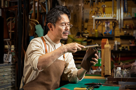 中年男性皮匠打磨皮具图片