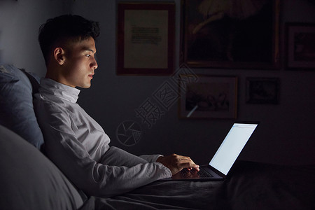 夜晚居家男士使用电脑加班办公打字图片