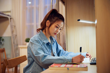 女大学生考研前在宿舍认真复习背景图片