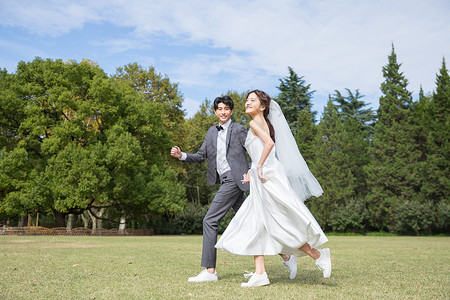 奔跑新娘在草坪上牵手奔跑的情侣背景